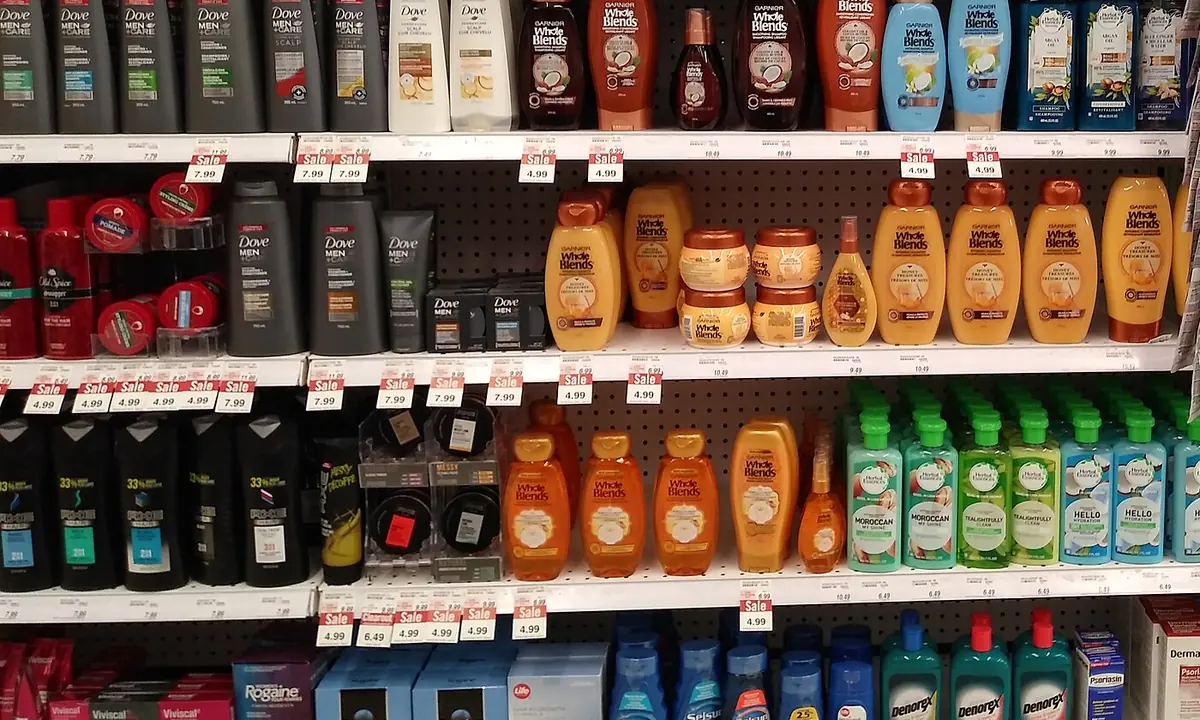 Drugstore shelving stocked with rows of hair and body care bottles.
