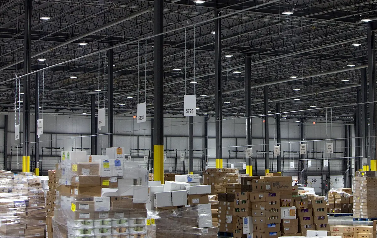 Wide view of a distribution warehouse floor with palletised cartons under steel racking.