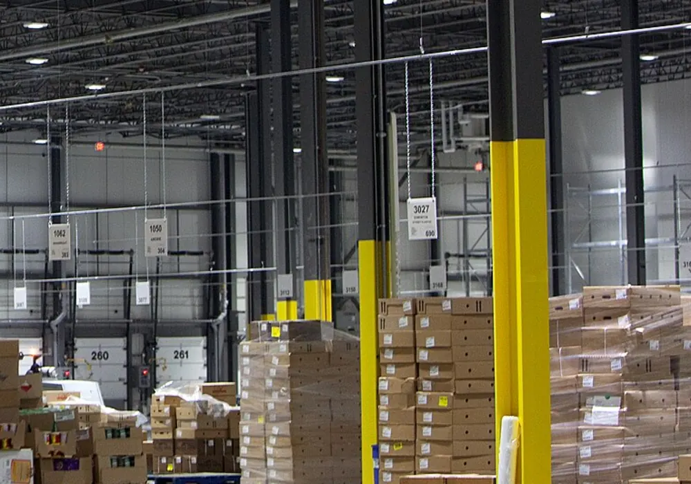 Palletised cartons staged under high bay lighting in a distribution warehouse.